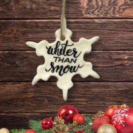 Whiter Than Snow ornament on wood background with red ornament garland below